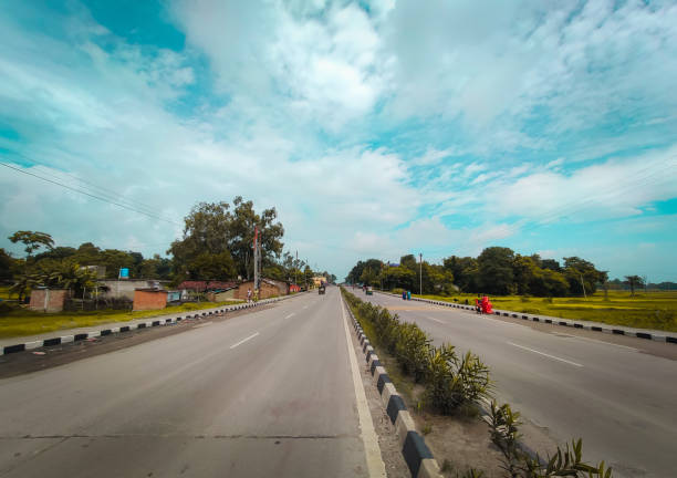 Indian Highway four lane road Indian Highway multiple lane road with bushes in the divider and beautiful blue sky and scenery denish stock pictures, royalty-free photos & images