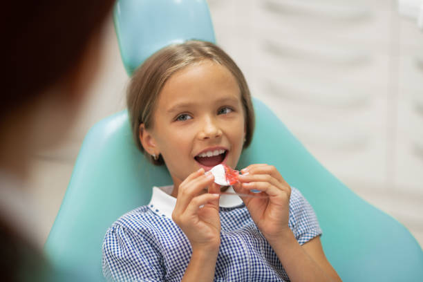 Girl smiling while putting mouth guard on her own Putting mouth guard. Beautiful blue-eyed girl smiling while putting mouth guard on her own sequence dress stock pictures, royalty-free photos & images