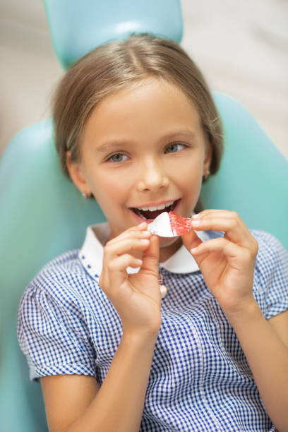 Girl wearing checked dress smiling while putting mouth guard Girl smiling. Appealing cute girl wearing checked dress smiling while putting mouth guard sequence dress stock pictures, royalty-free photos & images