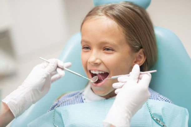chica linda sonriendo mientras visita al dentista el fin de semana - dentists chair dentist office dental hygiene clinic fotografías e imágenes de stock