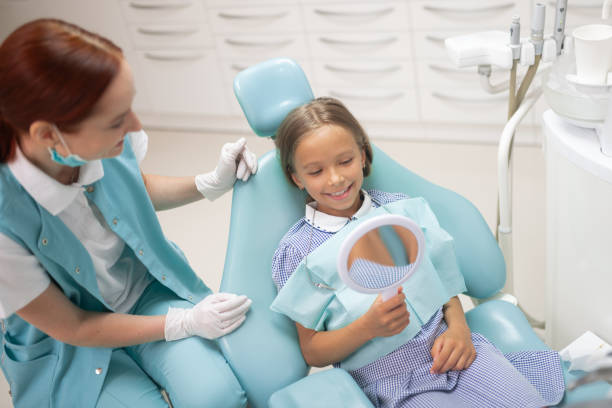 istock Girl smiling while looking into mirror sitting near dentist 1168420921