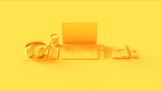 Configuración de la oficina del hot desk contemporáneo amarillo con las gafas de sol del bloc de notas de los auriculares del teléfono móvil del ordenador portátil photo