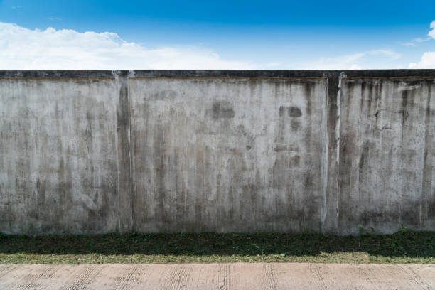 istock Old cracked gray cement or concrete wall with blue sky as background. Grunge plastered stucco  textured background. 1168423369