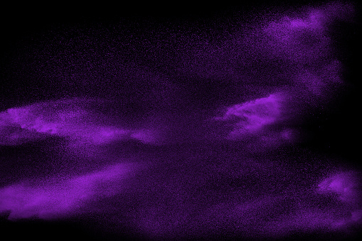 Purple particle dust splash on black background. Purple powder exploding.