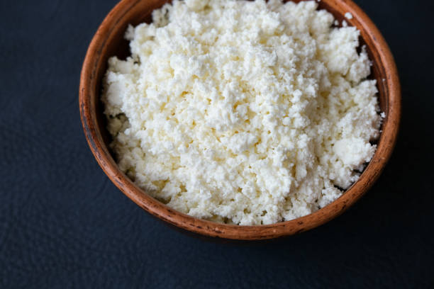 istock Cottage cheese in a brown bowl on a dark background. 1168427751