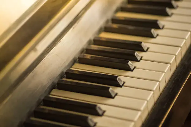 Photo of Piano keyboard background with selective focus, warm colors.