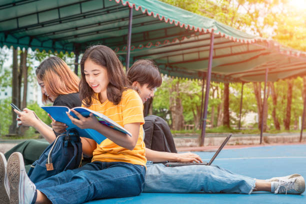 istock Group of Asian college student using tablet and mobile phone outside classroom. Happiness and Education learning concept 1168429236