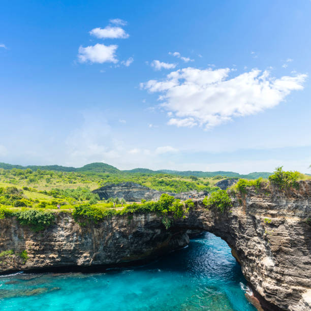 praia quebrada e louro rochoso da praia de billabong com céu a água azul do oceano e o céu azul aparte de uma viagem traval do dia do leste no console de nusa penida, regência de klingung, console de bali, indonésia - traval - fotografias e filmes do acervo