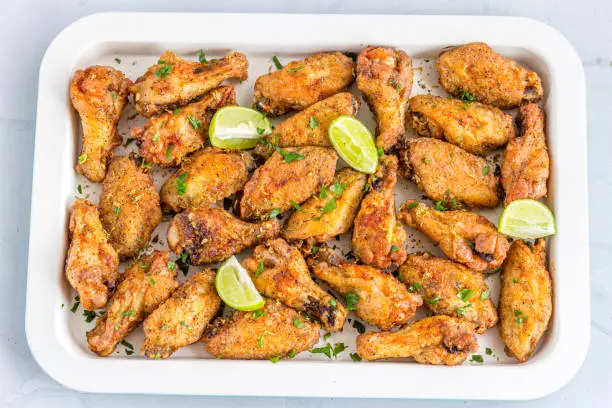 Crispy Fried Lemon Pepper Chicken Wings on a Tray on White Background.