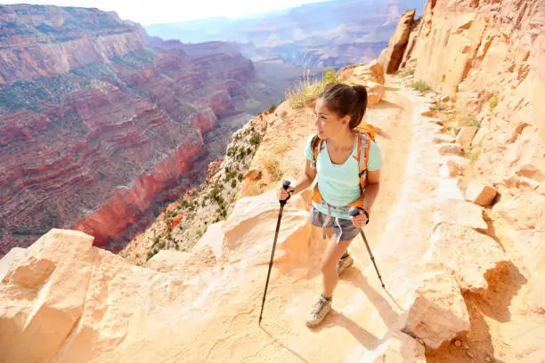 Hiker woman hiking in Grand Canyon walking with hiking poles. Healthy active lifestyle image of hiking young multiracial female hiker in Grand Canyon, South Rim, Arizona, USA.