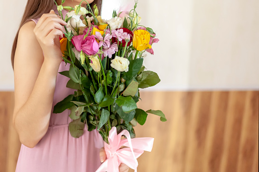 Beautiful middle-eastern girl with bouquet of flowers. Young attractive female with flowers. Portrait of charming, pretty girl holding bouquet. Romantic girl in fashionable dress. Birthday bouquet