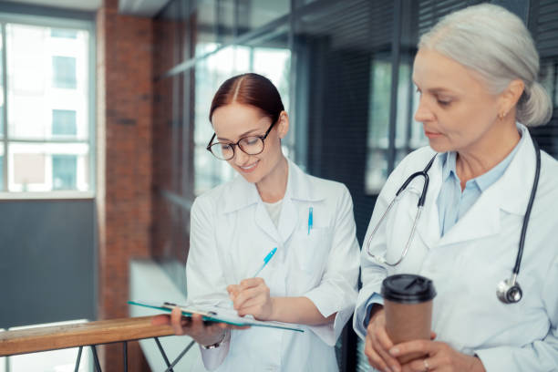 istock Woman in a white coat looking at her colleague 1168444727