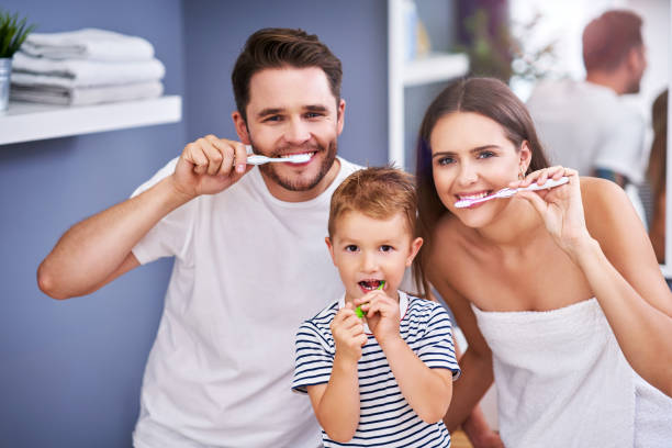 Portrait of happy family brushing teeth in the bathroom stock photo