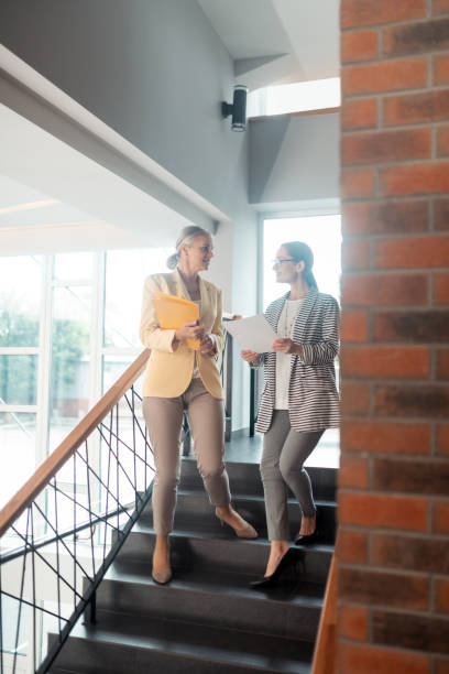 istock Two smiling business ladies going down the stairs 1168445759