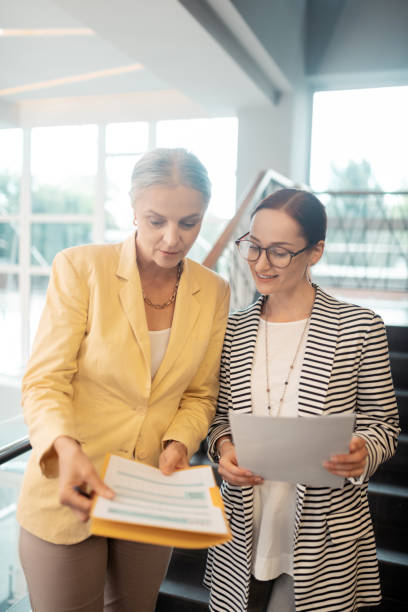 istock Serious senior woman showing documents to a colleague 1168445764