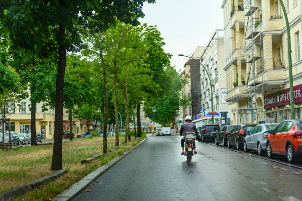 Berlin, Germany - July 13, 2019: Street scene with a moped driver on a Berlin street at a rainy day.