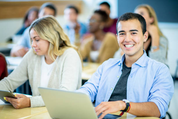 istock Student smiling at his desk with a laptop in front of him 1168447108