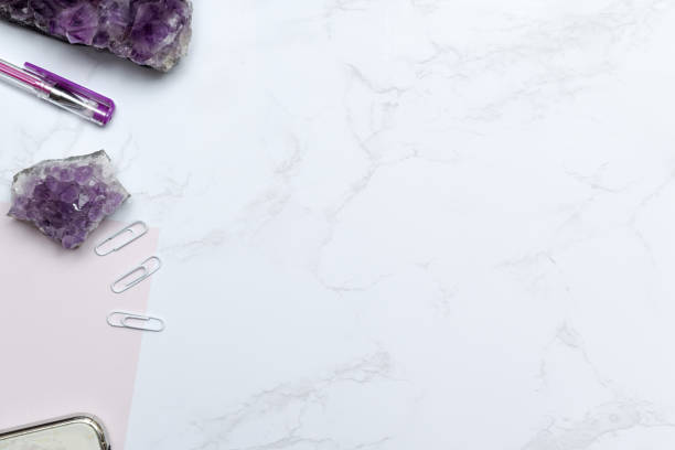 istock Purple themed stationary set with notebook and pen on a modern marble desk 1168448134