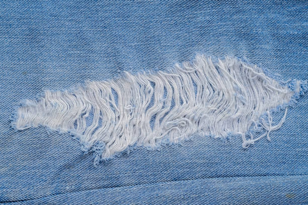 istock tear of denim texture with a hole and threads showing 1168450704