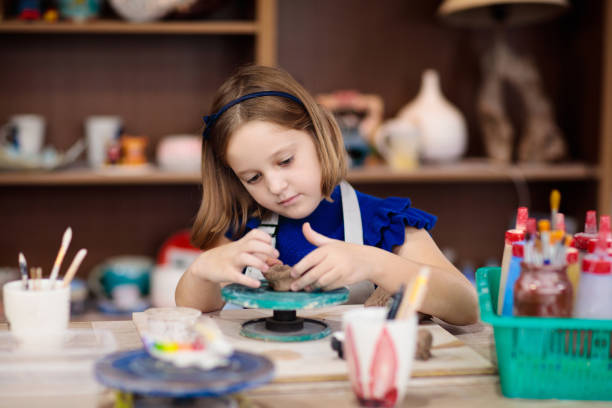 istock Child at pottery wheel. Kids arts and crafts class 1168452653