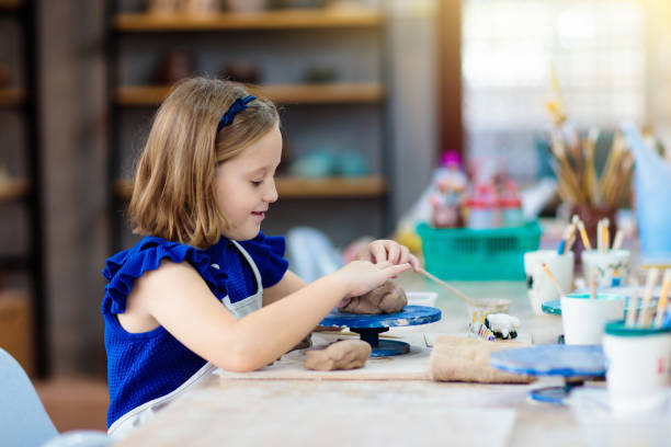 istock Child at pottery wheel. Kids arts and crafts class 1168452717