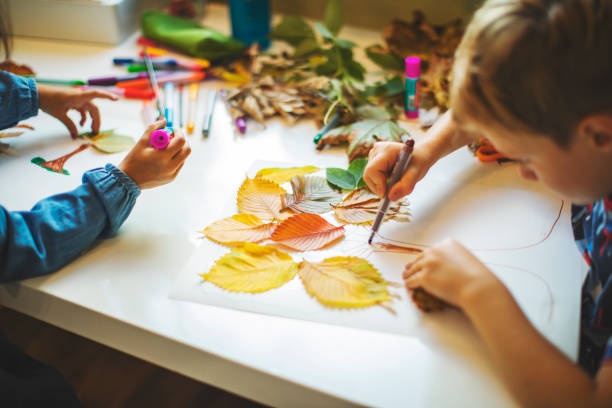 niños haciendo artesanías de otoño - actividades recreativas fotografías e imágenes de stock