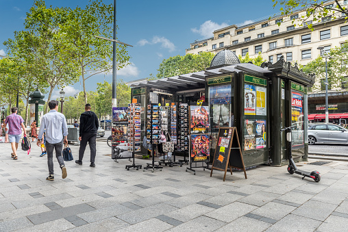 Paris, France - August 2, 2019: Tourists and passersby around a press kiosk and souvenirs in the Champs Élysées of Paris France.