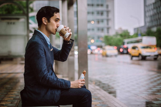 istock Businessman eating breakfast while waiting for a bus 1168459901