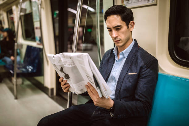 Reading news on his way to work place in subway Mixed race businessman sitting and Reading news on his way to work place in subway ear horn photos stock pictures, royalty-free photos & images