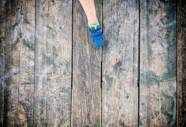 istock Children's foot on old plank floor 1168466455