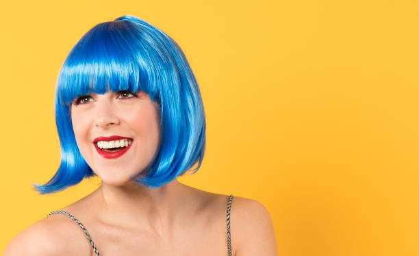 mulher nova de sorriso bonita com uma peruca azul em um fundo amarelo - blue hair - fotografias e filmes do acervo
