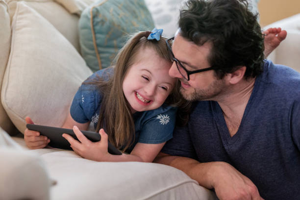 Young girl with Down Syndrome giggles with dad The young girl with Down Syndrome giggles with her mid adult father. chromosome photos stock pictures, royalty-free photos & images