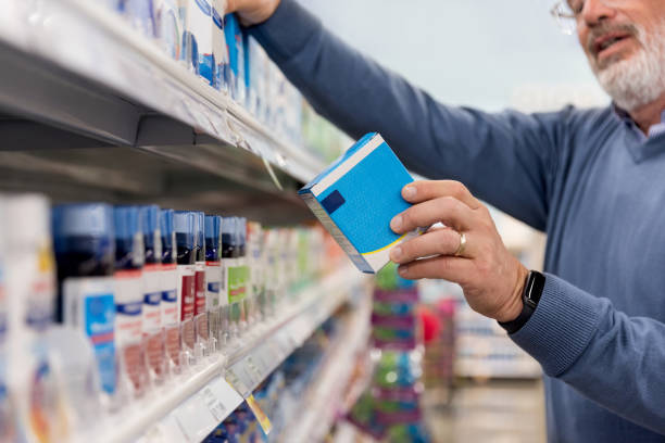Unrecognizable mature man reads medication instructions at pharmacy