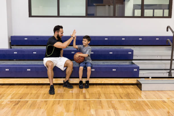 assis sur des gradins après jeu, le papa donne le fils haut cinq - sport parent bleachers family photos et images de collection