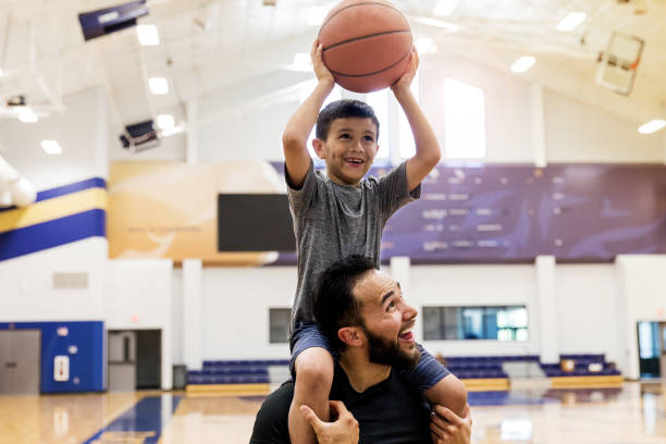 istock Uncle holds nephew on shoulders so nephew can make basket 1168467464