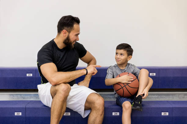 oncle adulte moyen enseigne les règles de basket-ball jeune neveu - sport parent bleachers family photos et images de collection