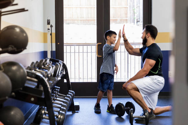 After his nephew works hard with the weights, the mid adult uncle gives him a high five.