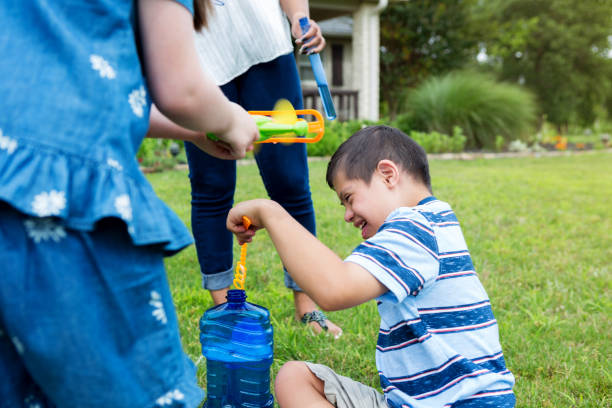 istock Siblings and mom play with bubble wands in house yard 1168467625