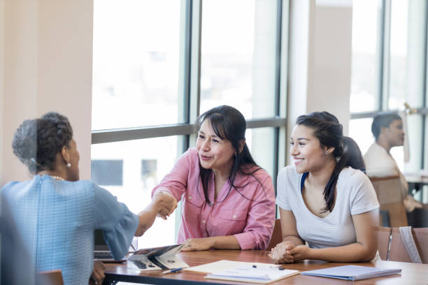 Women meet with loan officer Mature woman shakes hands with loan officer. She and her college age daughter are meeting with the loan officer about obtaining a student loan. college student and parent stock pictures, royalty-free photos & images