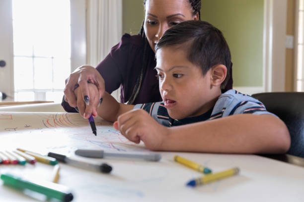 istock Female tutor helps boy with Down Syndrome 1168468435
