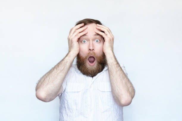 istock Bearded man holds head in hands and opens mouth in surprise 1168469018