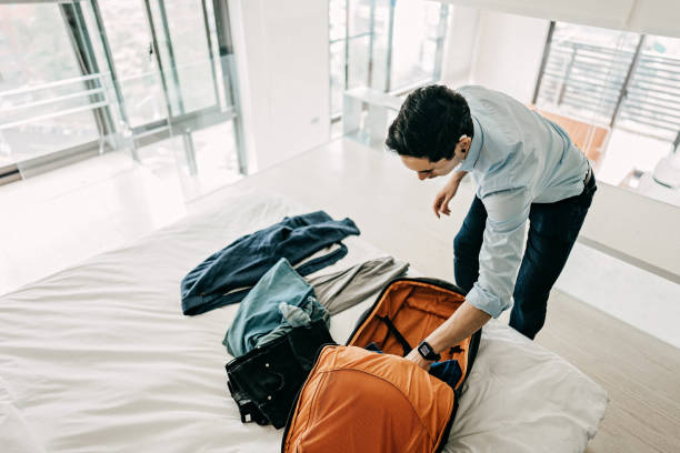 Young Businessman packing suitcase for business travel Young Businessman packing suitcase for business travel ear horn photos stock pictures, royalty-free photos & images