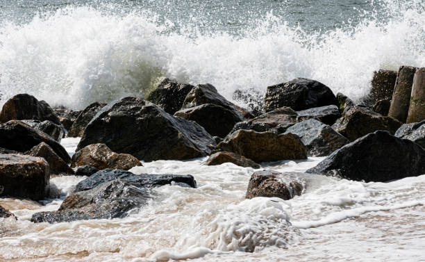 ocean waves crashing onto black rocks on the waters edge - waters edge wave beach soap sud imagens e fotografias de stock