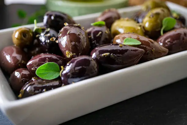 White tray with olives and fresh herbs. Close up