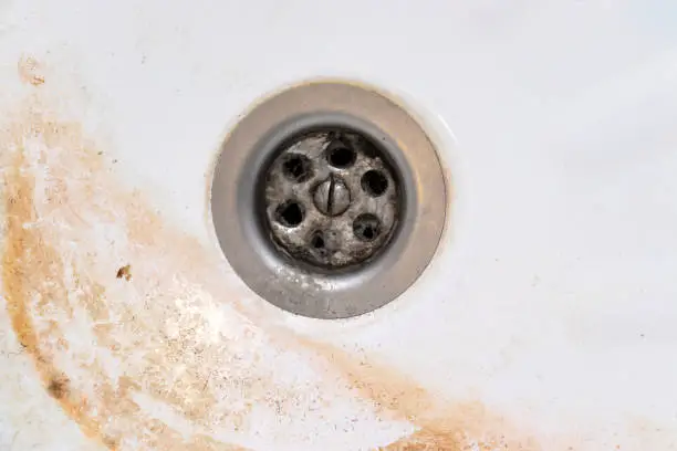 Dirty sink drain mesh, hole with limescale or lime scale and rust on it close up, dirty rusty bathroom washbowl.