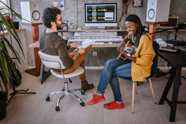 サウンドレコーディングスタジオで音楽を作る多民族カップル - headphones women tattoo music ストックフォトと画像