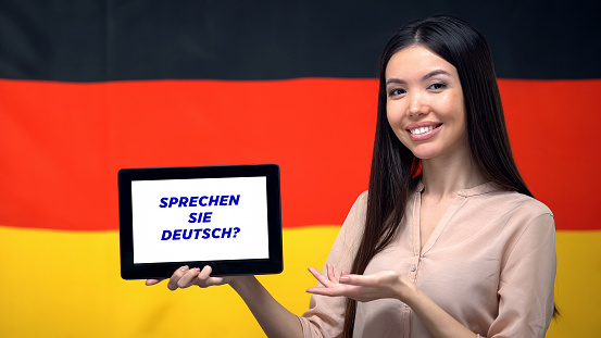 Woman holding tablet with do you speak german phrase, app for learning language