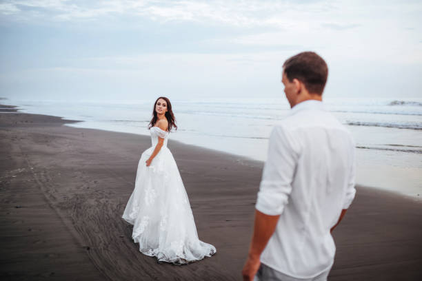 istock Elegant gorgeous bride and groom walking on ocean beach during sunset time. 1168480510