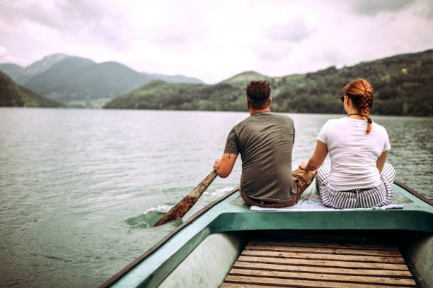 coppia su piccola barca sul lago - canoeing people traveling camping couple foto e immagini stock