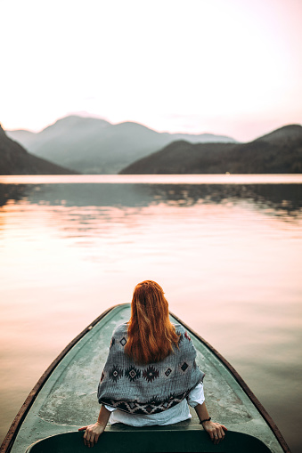 Rear view of woman sitting on small boat, floating and enjoying in view on lake
